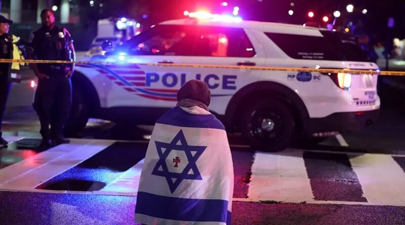 Um homem com uma bandeira israelense sobre os ombros se ajoelha no meio da rua, perto de um carro da polícia de Washington, D.C., no local do tiroteio mortal. REUTERS